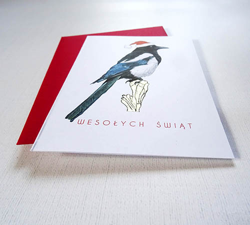 Elegancka Kartka Świąteczna z Sroką w Mikołajkowej Czapce, Ręcznie Ilustrowana wraz ze Złotymi Detalami i napisem Wesołych Świąt.